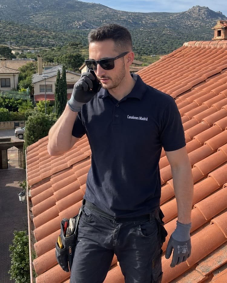 Técnico de Canalones.Madrid en un tejado de la Sierra de Madrid, hablando por teléfono